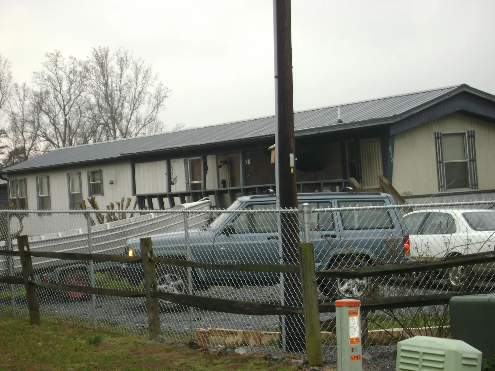 Dark metal roof on a long single story building behind a chain link fence in Greenwood